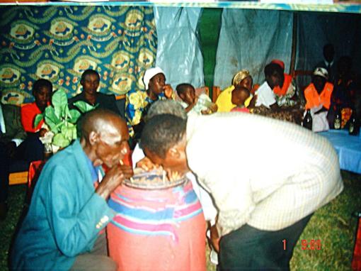 The two fathers, Omer and Deo, symbolically dring home-made sorghum brew.  Joint dringing of sorghum beer is a traditional part of the ceremony, and after they finish different members of the family will come to take some symbolic sips