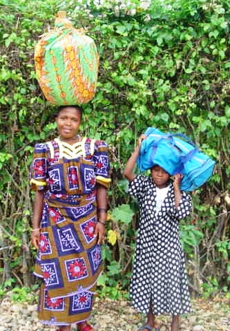 Evonne's younger sister, Elianne, is dressed in her new smock and with a cousin is coming with a traditional basket of beans for the newly-engaged couple